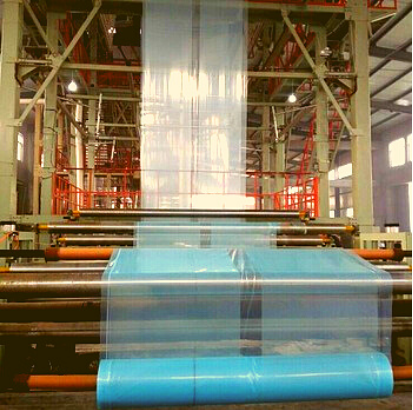 Greenhouse-plastic-being-rolled-onto-roll-by-machine